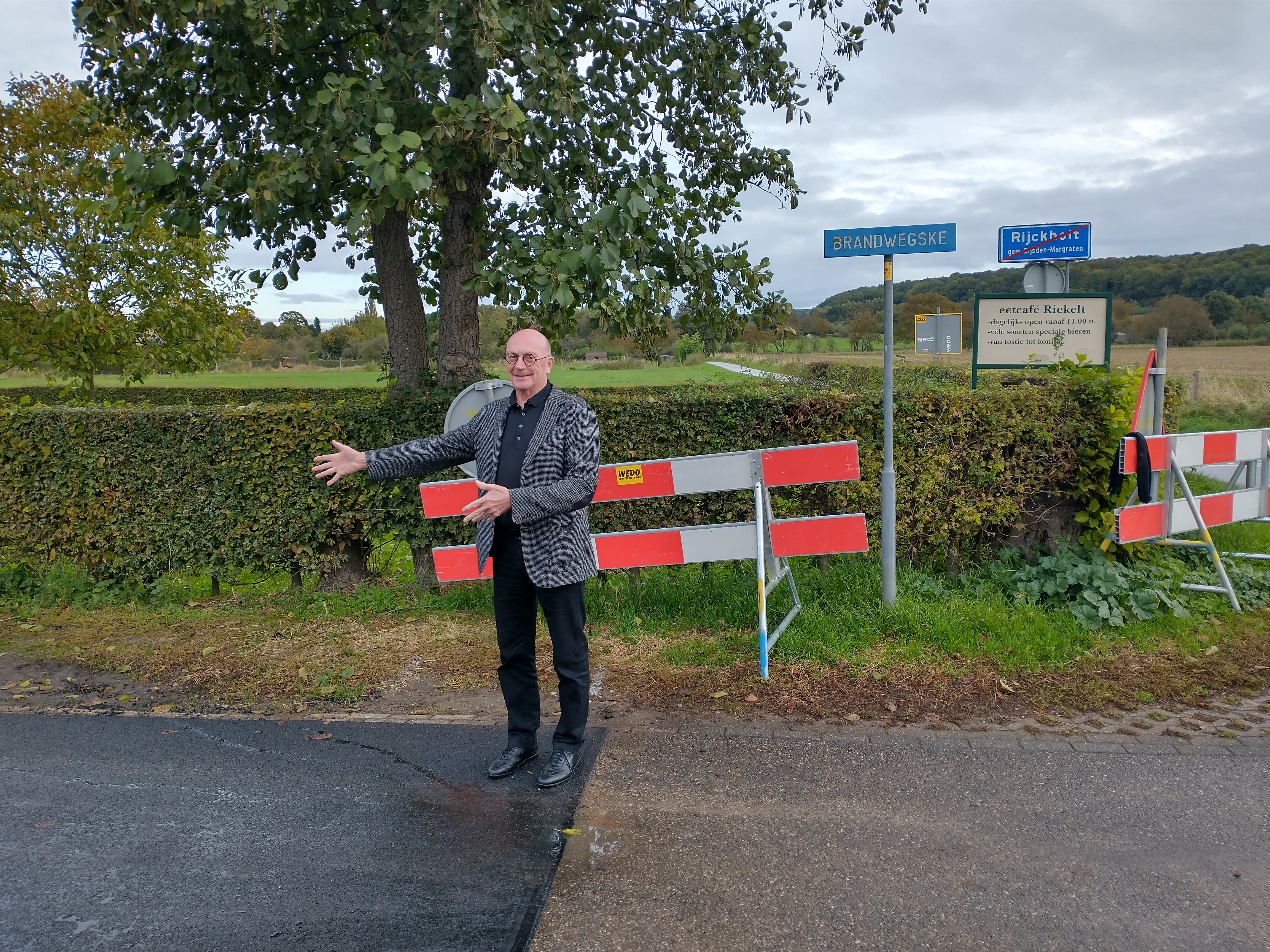 Wethouder Jan Weling op een straat die deels opnieuw geasfalteerd is. 